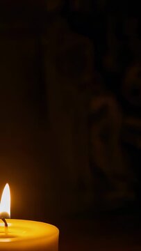 Vertical video: Flames sending rising smoke from two wax pillar candles on table creating warm glow