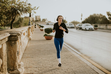 Woman running in Malta during daylight on a sidewalk beside a road