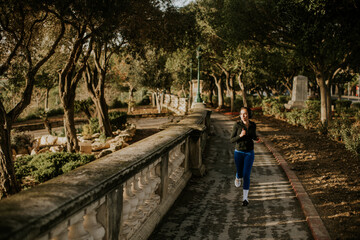 Obraz premium Woman jogging in Malta park during daylight near trees and pathway