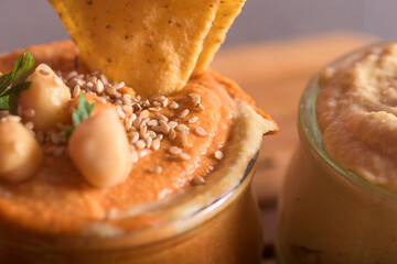 Close up of creamy hummus texture topped with organic chickpeas flax seeds and olive oil in a bowl