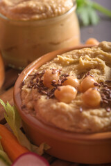 Close up of creamy hummus texture topped with organic chickpeas flax seeds and olive oil in a bowl