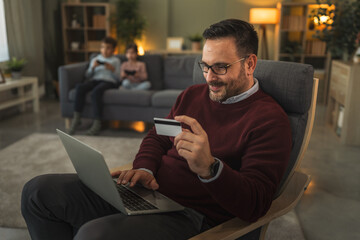 Father using laptop for online shopping with credit card at home