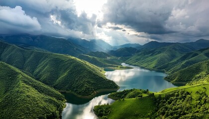 aerial view of lush green mountains and a serene lake under a cloudy sky