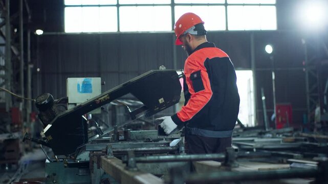 Manufacture working man at the factory wearing the safety equipment and helmet he take a piece of metal and measure the metal before to cut off with the machinery