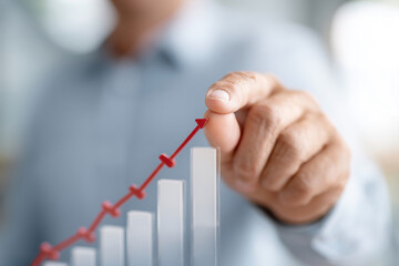 A man is drawing a red arrow on a graph, indicating a positive trend