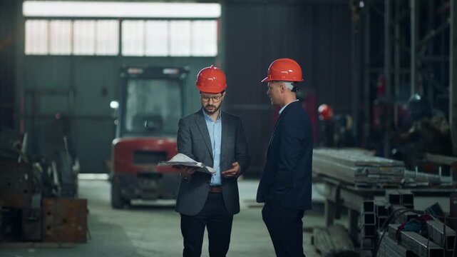 In front of the camera engineer and investor have a discussion in the production zone in the manufacturing factory about the plan of work and future projects