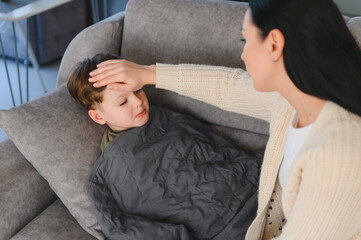 Fototapeta premium Mother checking sick boy's forehead for fever