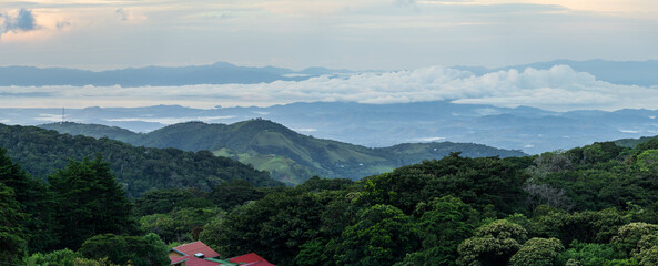 View west from Monteverde resort at sunrise over the hills towards Pacific ocean in broad panoramic format