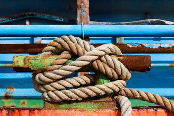 Fototapeta premium Rusty mooring bollard with tied ship rope in the port