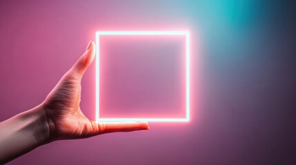 A person's hand elegantly holds a luminous neon square sign, radiating a colorful glow against a gradient backdrop, symbolizing modernity and creativity in design.