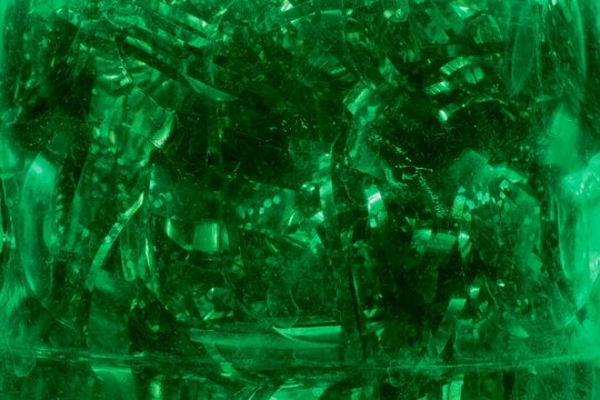 Abstract background of emerald green glass with internal textures.