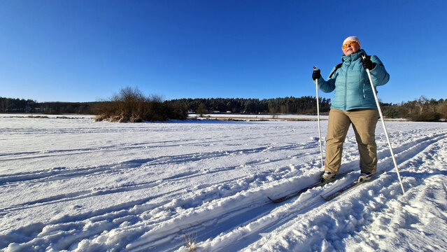Mature woman skiing on trail in winter cold weather. Cross-country skier in snowy National park Sumava, Czech Republic.