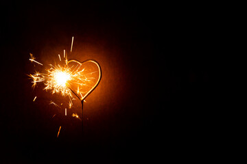 Cierge magique en forme de coeur scintillant, étincelles dorées sur un fond brun foncé, halo de lumière, déclaration d’amour, Saint Valentin