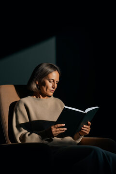 Woman Reading Book in Minimal Dark Interior &ndash; Calm Lifestyle Concept
