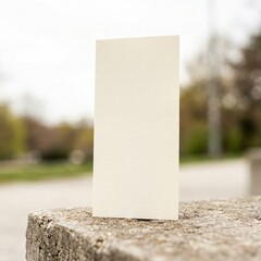 Blank White Card Standing Upright on a Textured Stone Surface Outdoors.