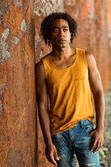 A young handsome man,an African model, walks alone, in a yellow T-shirt and jeans, in an unusual place
