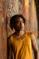 A young handsome man,an African model, walks alone, in a yellow T-shirt and jeans, in an unusual place