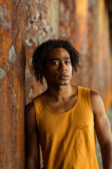 A young handsome man,an African model, walks alone, in a yellow T-shirt and jeans, in an unusual place