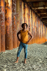 A young handsome man,an African model, walks alone, in a yellow T-shirt and jeans, in an unusual place
