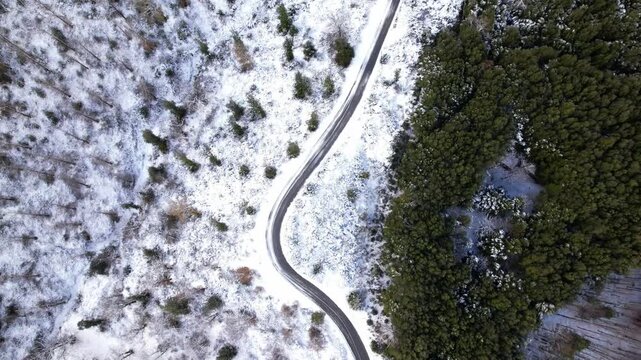 Drone video of a winding road. Aerial view of a winding mountain road in a winter forest.
A turn on a snowy forest road. A sharp turn on a mountain road among pine trees and white snow.