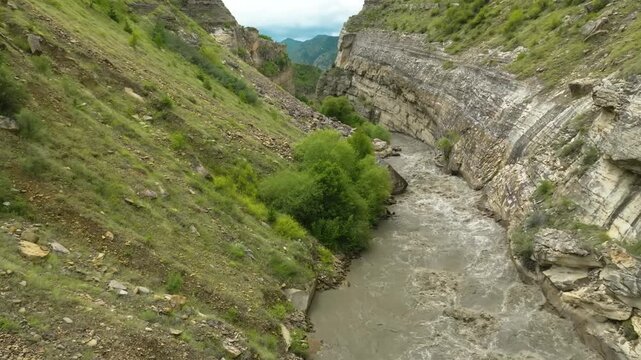 aerial footage of the Kara-Koisu River in the Republic of Dagestan, Russia. The drone shot captures the river winding through a picturesque mountain gorge, surrounded by lush green slopes and rocky cl