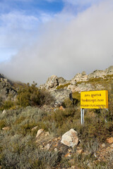 Translation: Military zone, no entry, danger of explosions. Information sign in a mountainous area, yellow in color, warning of the boundaries of a military exercise zone.
