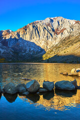Mountain Reflected in Tranquil Lake with Boulder Shoreline at Sunset