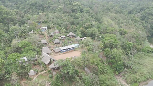 Aerial drone view of Embera Drua indigenous village located along the Chagres River in Colon, Panama. This cinematic scene showcases traditional huts, river landscape, and surrounding tropical rainfor