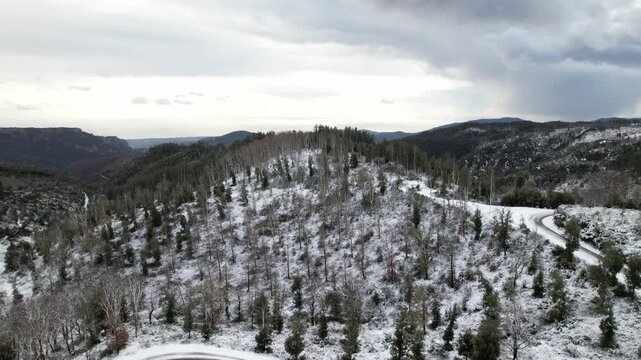 Drone video of a winding road. Aerial view of a winding mountain road in a winter forest.
A turn on a snowy forest road. A sharp turn on a mountain road among pine trees and white snow.