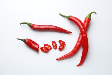 Fresh red chili peppers on white background, flat lay. Whole and sliced