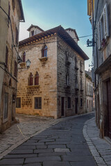 Obraz premium A quiet, narrow stone street in Vodnjan, Istria, lined with historic stone buildings, shuttered windows, and a warm Mediterranean atmosphere