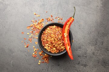Red chili pepper flakes on grey table, flat lay
