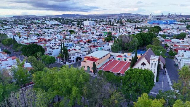 Church "Parroquia Sagrada Familia" in Queretaro, located among parks in an urban area aerial view