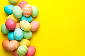 Many painted Easter eggs on yellow background, flat lay. Space for text