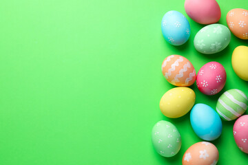 Beautiful decorated Easter eggs on green background, flat lay. Space for text