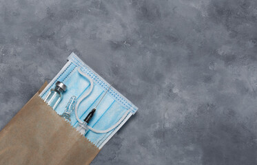 A paper bag with a medical mask, a medical syringe and medicine in ampoules.