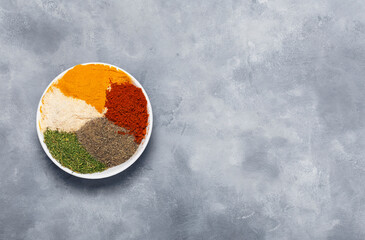 Spices: black pepper, dried dill, dried garlic and paprika on a round dish, top view.