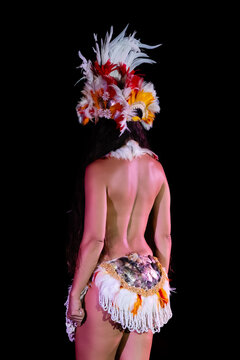 Poised Tahitian dancer in lauhala headdress and traditional skirt, viewed from behind in a powerful moment that honors Polynesian culture, ancestral roots, and expressive island arts and tradition.