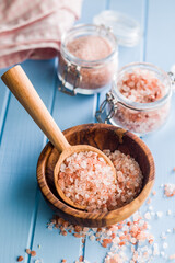 Fototapeta premium Pink Himalayan salt on wooden spoon on blue table.