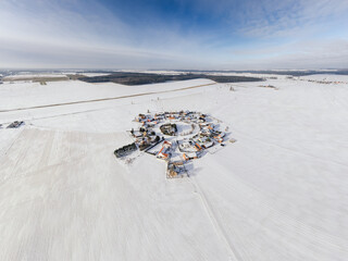 Aerial winter view of Gronowice, known as the Red Village, Poland. Snow-covered red rooftops and rural landscape captured by drone.