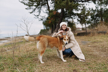 Woman, dog, outdoors, companionship, coat, fall scene with a smiling pair enjoying a chilly park...