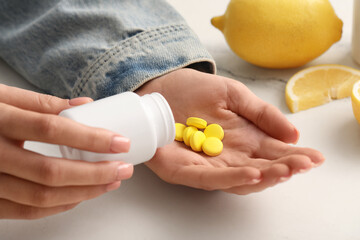 Woman taking vitamin C pills at marble table