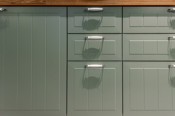 Sage green kitchen fronts with white handles and wood counter. Green kitchen.