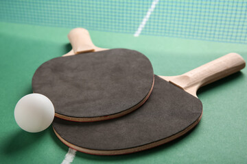 Ping pong rackets and ball on green table