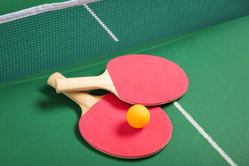 Ping pong rackets and ball near net on green table
