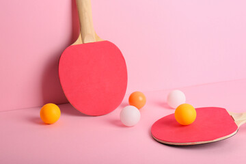 Red ping pong rackets and balls on pink background
