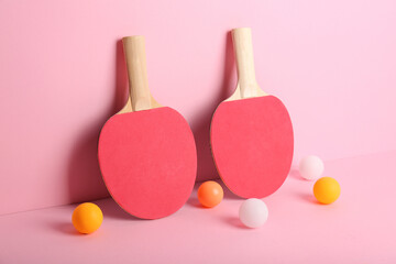 Red ping pong rackets and balls on pink background