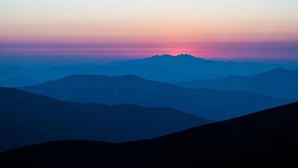Obraz premium Majestic mountains silhouetted against a vibrant dusk sky at sunset from a distant viewpoint