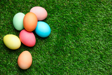 Fototapeta premium Beautiful decorated Easter eggs on green grass outdoors, flat lay. Space for text