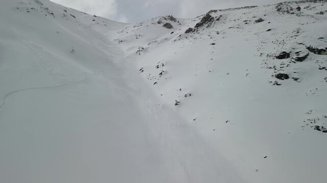 A snowboarder makes fluid turns down a remote, untouched slope in Gulmarg, Kashmir. The fresh snow, dynamic carving tracks, and serene winter landscape highlight the thrill of freeriding
